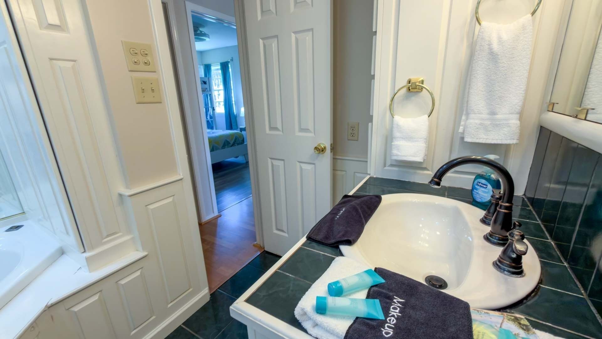 Une salle de bain équipée d’un lavabo, d’un porte-serviettes et d’une porte donnant sur une chambre.