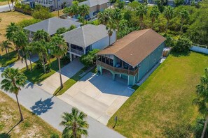 A residential property with a large house, a covered porch, and a well-maintained lawn with palm trees. - Unique 2 In 1 Bayviews Pool 3 Bedroom Condo (South Padre Island)