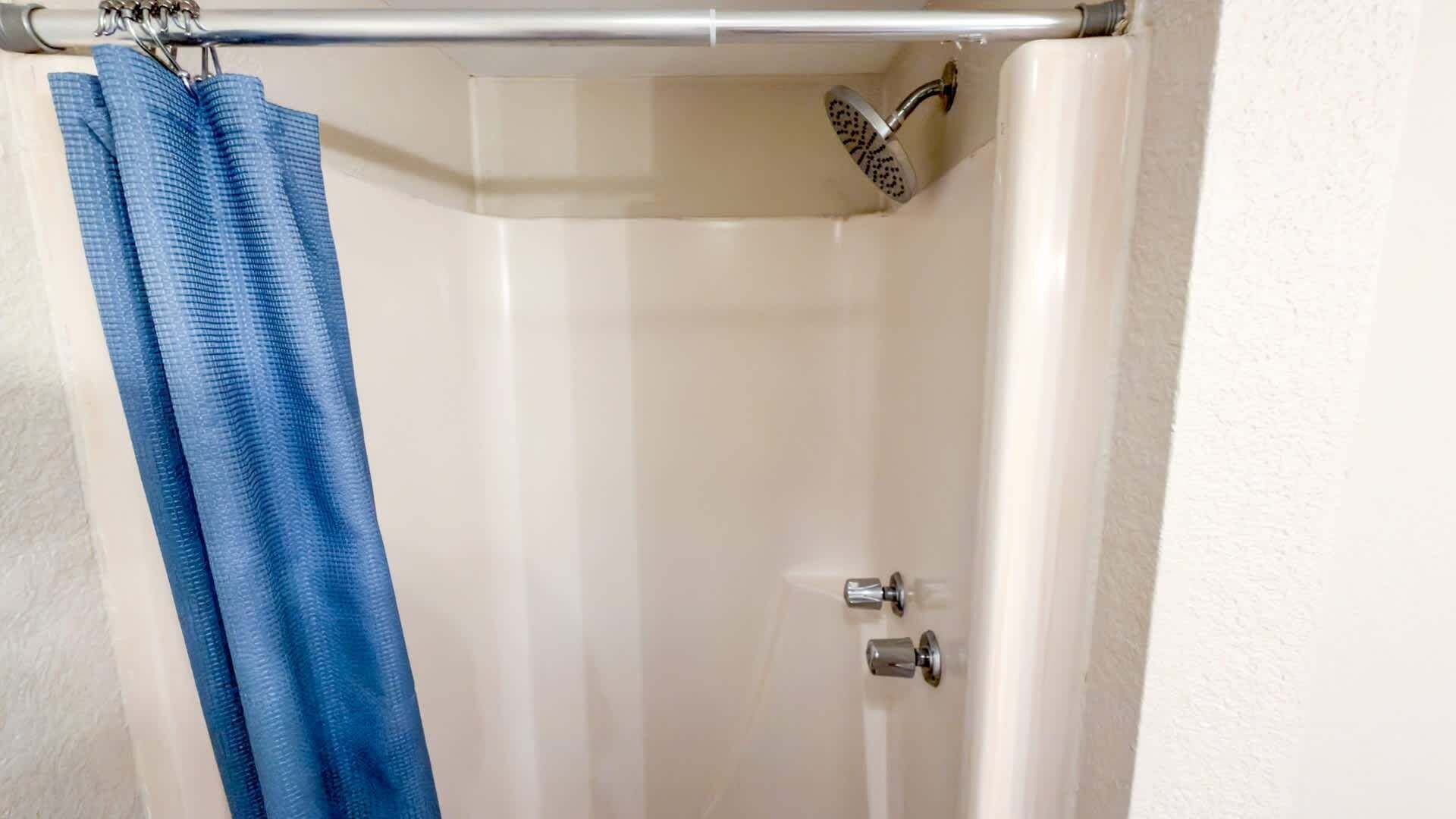 Une salle de bain avec une douche, une baignoire blanche et un rideau de douche bleu.