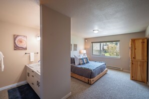 A bedroom with a bed, a window, a wooden wardrobe, and a bathroom with a sink and towel rack. - Candlelight Meadows Escape | Hot Tub Near Town Center & Spacious Great Room (Big Sky)