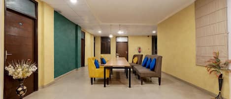 A conference room with a long table, yellow and brown chairs, and a sofa with blue cushions.