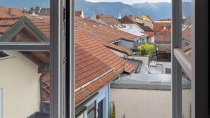 Une vue depuis une fenêtre, donnant sur une ville et des montagnes au loin.