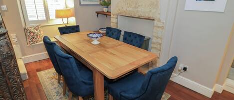 Un comedor con una mesa de madera y sillas tapizadas en azul, un tapete estampado y una chimenea de piedra.