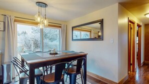 Un espace repas comprenant une table, des chaises, un lustre et un grand miroir au mur.