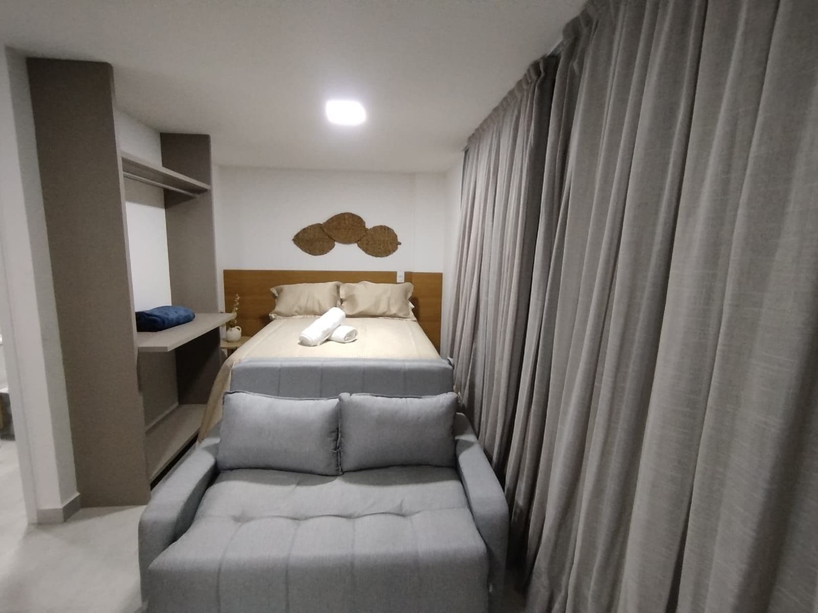 Una habitación de hotel con una cama, un sofá, una mesita y un adorno en la pared.