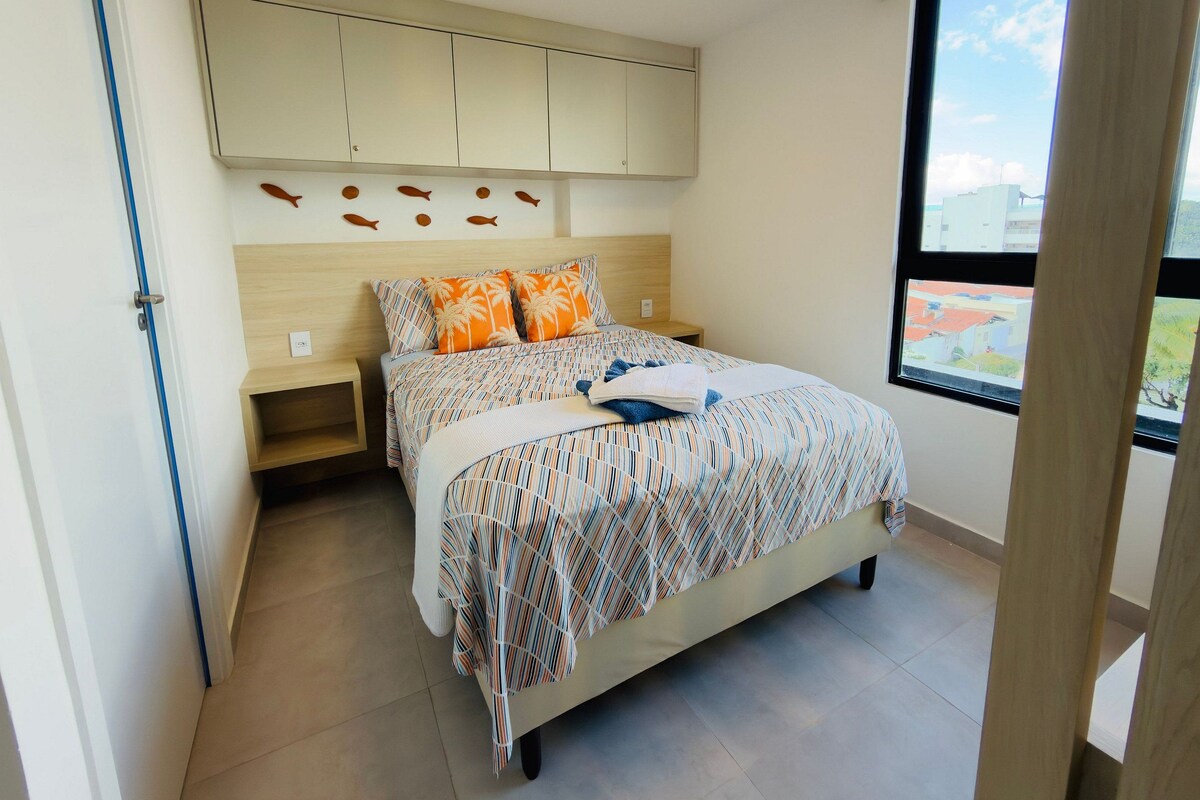 Ein Schlafzimmer mit Bett, Nachttisch, Einbauschrank und einem Fenster mit Blick.