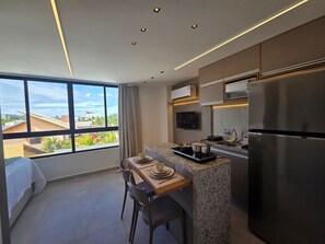 A modern kitchen with a large window, a dining area, and a built-in refrigerator. - Carneiros Beach Exclusive (Tamandaré)
