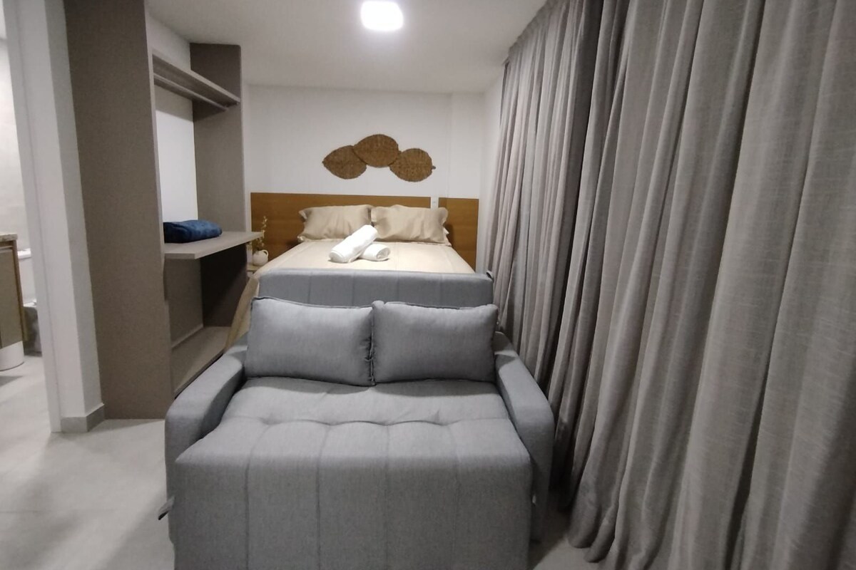 Ein modernes Hotelzimmer mit Bett, einer Sitzecke und einer Dusche.