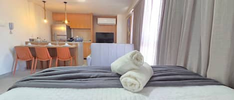 Una habitación de hotel con cama, kitchenette, comedor y televisor.