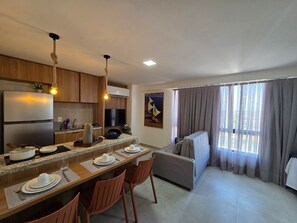 Eine moderne Küche mit integriertem Kühlschrank, ein Essbereich mit Tisch für Zwei und ein Sofa im Wohnbereich.