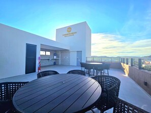 A rooftop terrace with a table and chairs, a small kitchenette, and a view of the city. - Carneiros Beach Exclusive (Tamandaré)