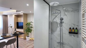 A modern bathroom with a glass-enclosed shower, marble walls, and a built-in shelf with toiletries. - Elegant Suites in the Heart of Piraeus (Piraeus)