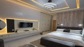 Ein modernes Schlafzimmer mit einem großen Bett, einem an der Wand montierten Fernseher und einem minimalistischen Design.