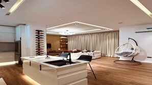 Eine moderne Küche mit einer zentralen Kochinsel, ein Essbereich mit einer Couch und einem Hängekorbstuhl, sowie ein Wohnzimmer mit einer Chandelieber.