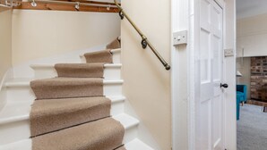 A staircase with beige carpeted steps, a white handrail, and a wooden banister. - South Street (No 16A) | Elie (Elie)