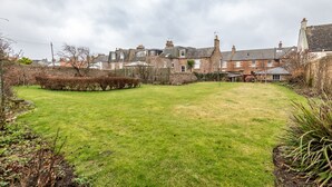 A residential area with a well-maintained lawn, stone walls, and traditional houses with pitched roofs. - South Street (No 16A) | Elie (Elie)