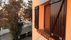 A balcony with a wooden door and window shutters, a stone pathway, and a tree. - Alma CaloRosa – Sea View Escape in Romantic Moledo, Northern Portugal (Moledo)