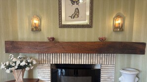 A fireplace with a brick surround, a wooden mantel, and two wall sconces. - Alma CaloRosa – Sea View Escape in Romantic Moledo, Northern Portugal (Moledo)