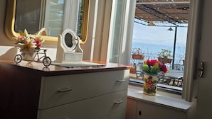 Een kamer met een dressoir, een spiegel, een klein fietsje en een vaas met bloemen.