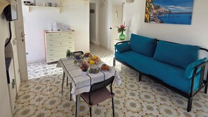 Een kamer met een eettafel gedekt met eten, een bank en een schilderij van een kustgezicht.