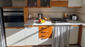 Een keuken met witte kastjes, een fornuis, een broodrooster en een spoelbak.