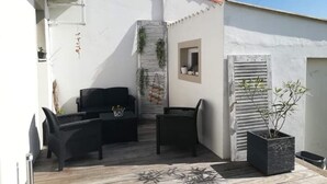 A patio with two black wicker chairs, a small table, and a potted plant. - Detached house with garden, close to the sea. (Saint-Hilaire-de-Riez)