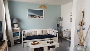 A living room with a sofa, coffee table, and a painting on the wall. - Detached house with garden, close to the sea. (Saint-Hilaire-de-Riez)