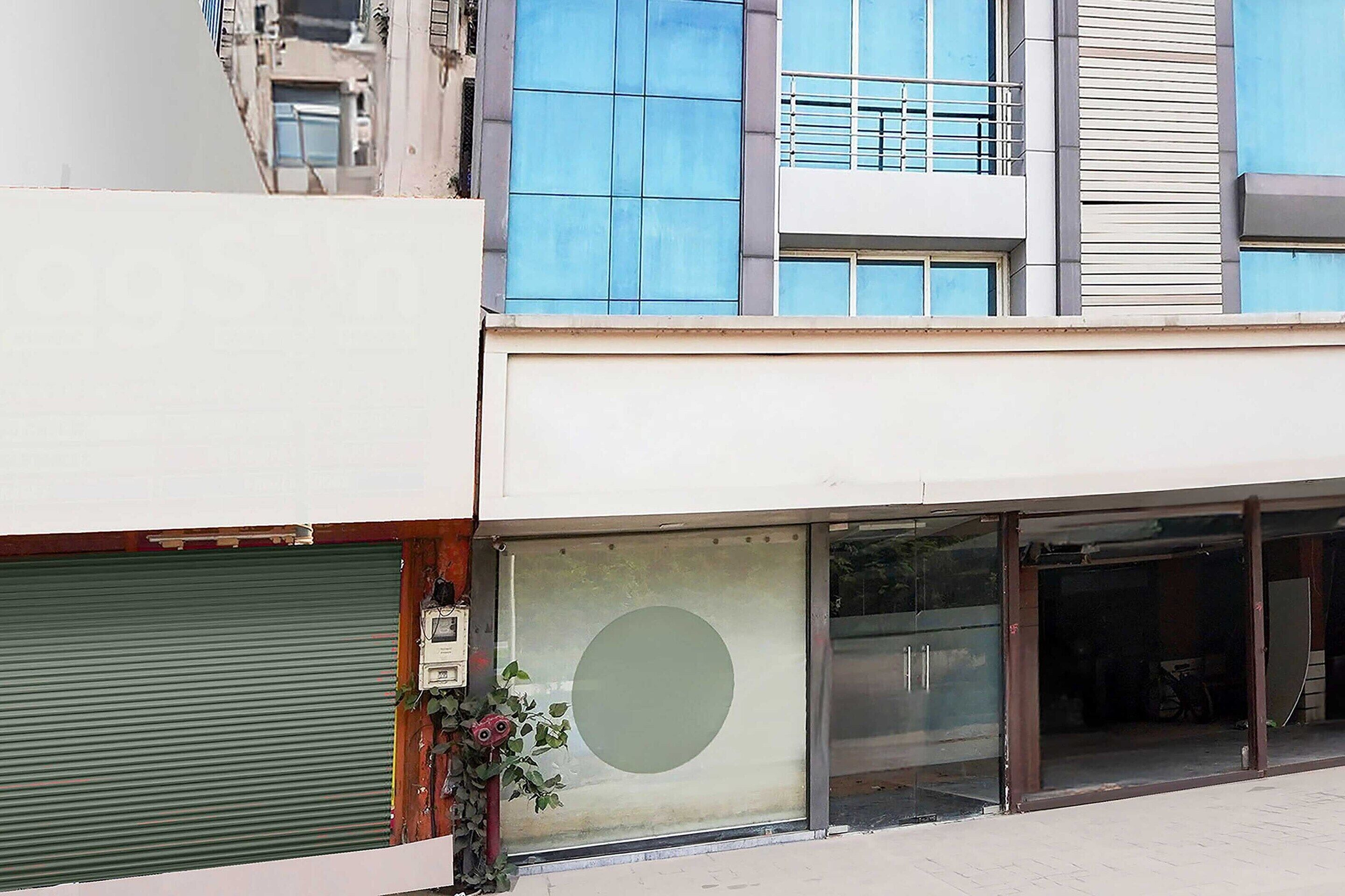 Un edificio con una vetrina dotata di persiane verdi, un'ampia finestra circolare e un balcone con ringhiere.