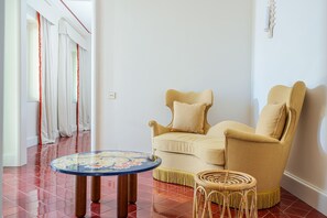 A room with a beige sofa, a small round table, and a wicker chair. - Villa Helios Capri (Capri)