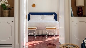 A bedroom with a bed, two bedside tables, a chandelier, and a wicker basket with flowers. - Villa Helios Capri (Capri)