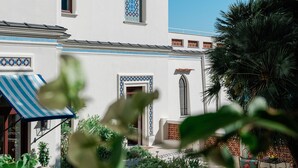 A white building with blue decorative tiles, a garden with plants, and a patio area. - Villa Helios Capri (Capri)