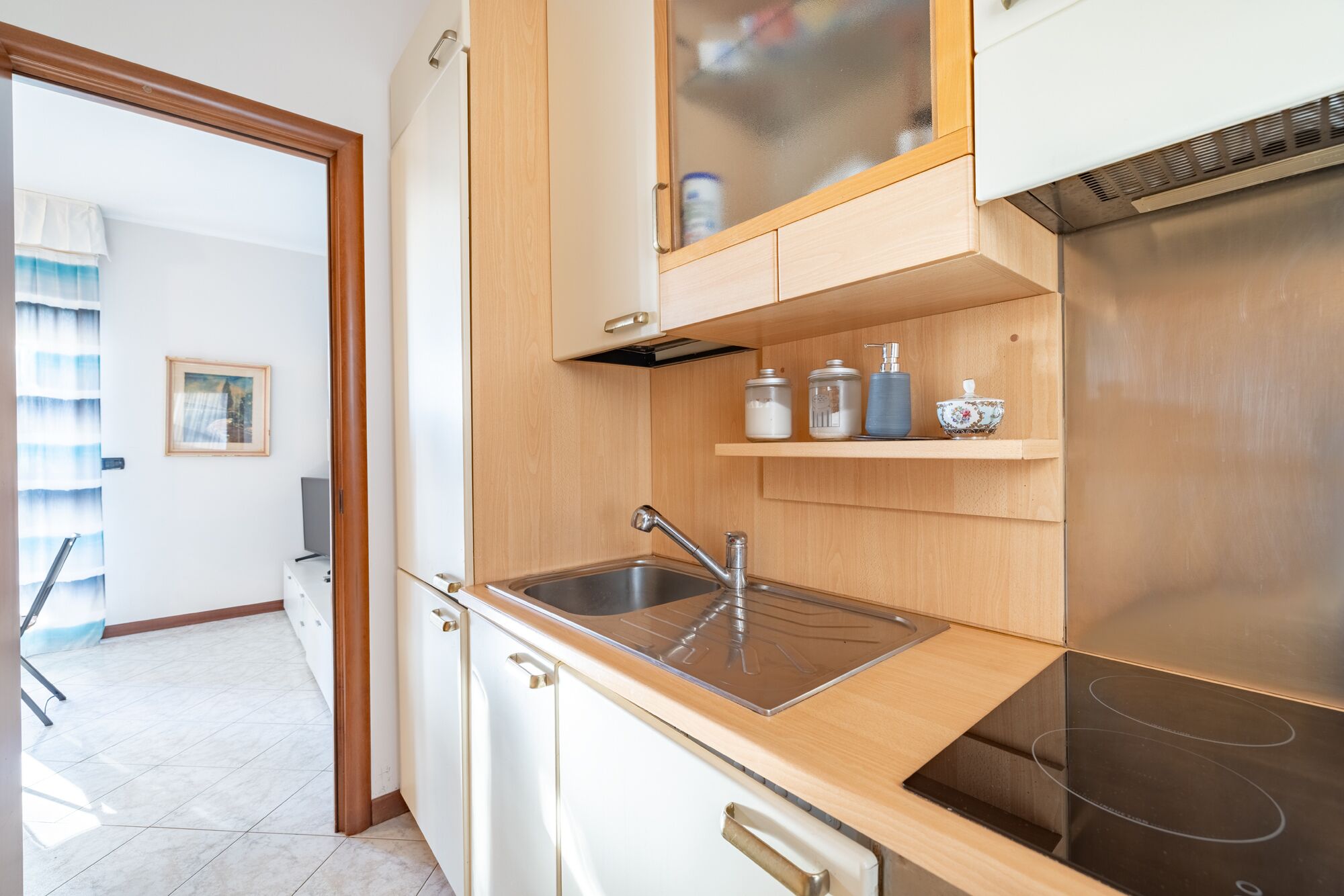 Une cuisine moderne dotée d’un évier en acier inoxydable, de meubles en bois et d’une cuisinière intégrée.