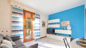 Ein Wohnzimmer mit grauem Sofa, Fernseher und einer blauen Akzentwand.