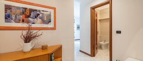 A hallway with a wooden console table, a framed picture, and a bathroom visible through an open door.