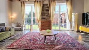Un soggiorno ampio con una grande finestra, un soffitto in legno, un tavolo rotondo e una TV.