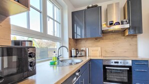 Una cucina moderna con forno integrato, microonde e lavandino.