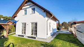 Una moderna casa a due piani con tetto spiovente, ampie finestre e un prato curato.