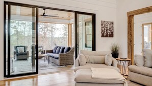 A spacious living room with a large sliding glass door leading to an outdoor area, a ceiling fan, and a modern fireplace.