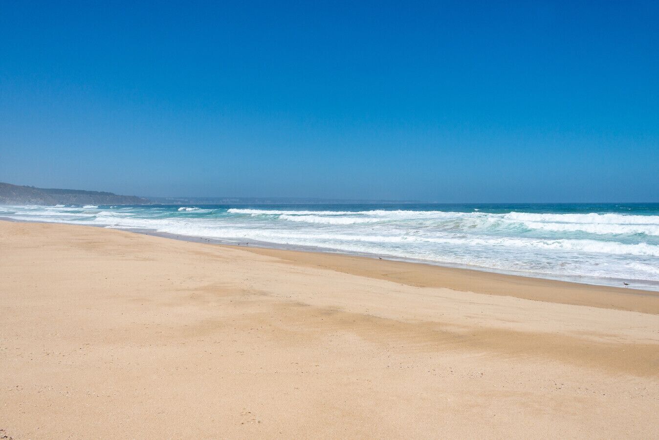 A beach with a clear sky and waves.