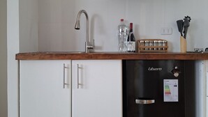 A compact kitchen with a sink, a refrigerator, and a wooden countertop. - Oceanfront Apartment Estudio el Suspiro (Tunquen)