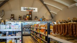 A pharmacy interior with shelves stocked with various products, a refrigerated section, and a sign reading "WINKELTJE". - 2 minutes from the beach! Mobile home Duingras Ameland (Nes)