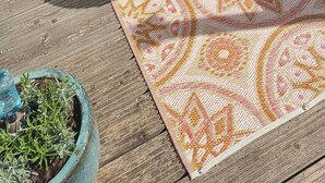 A patio with a round table and a patterned rug, a potted plant, and a wooden bench. - 2 minutes from the beach! Mobile home Duingras Ameland (Nes)