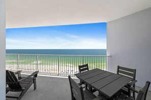 A balcony with a view of the beach and ocean, a table, and chairs. - Lighthouse 1215 by Liquid Life (Gulf Shores)