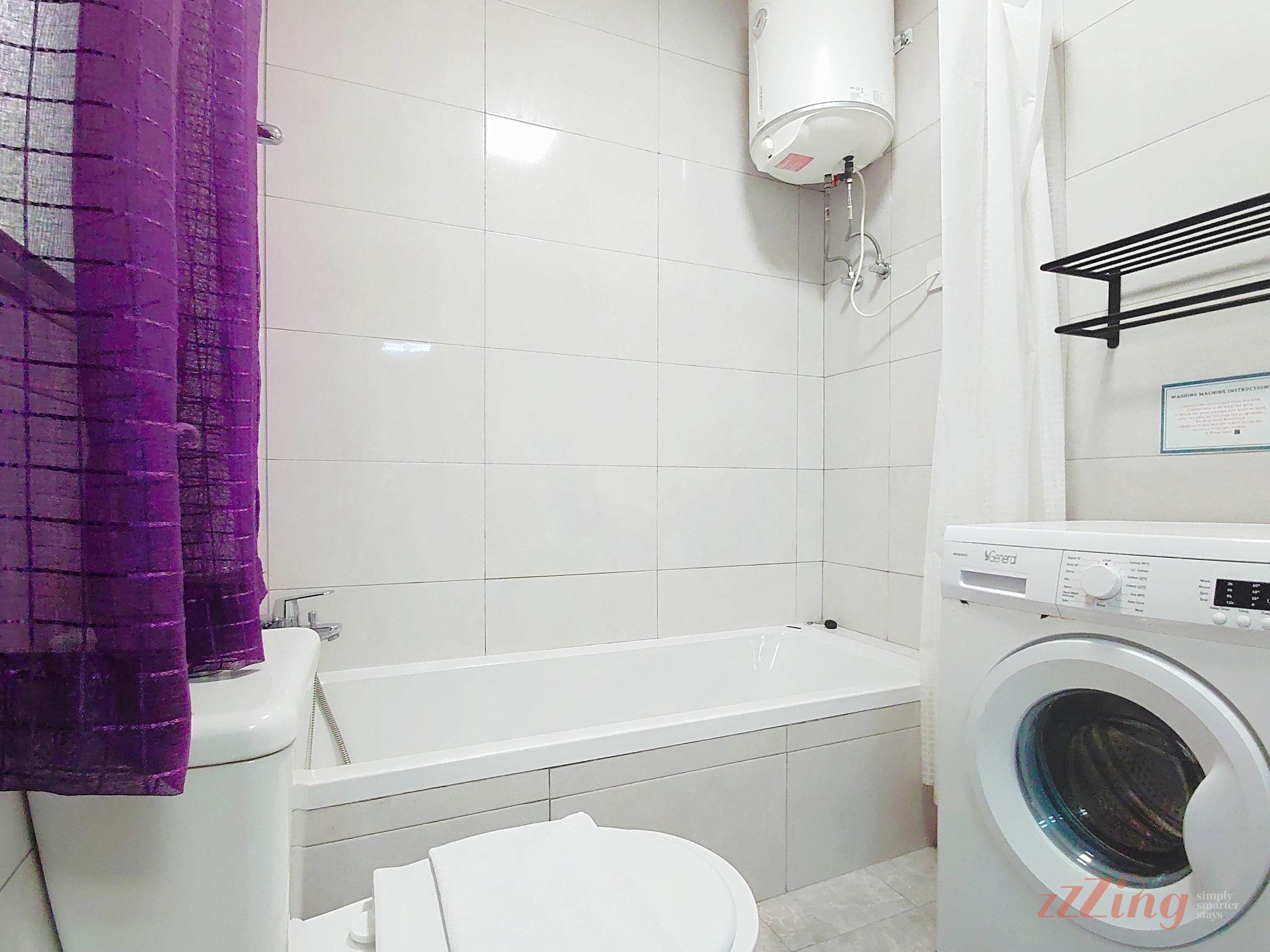 Une salle de bain avec une baignoire, des toilettes et un lave-linge.