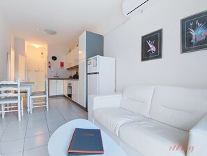 Una sala de estar moderna con un sofá blanco y una zona de comedor con una mesa y sillas blancas.