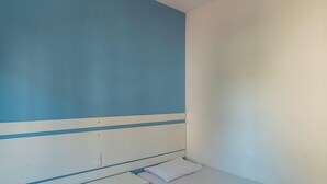 A room with a blue and white color scheme, a bed with a white pillow, and a visible electrical outlet on the wall. - Apt in Condo w/ Pool 350m From the Beach Pvj0021 (Ubatuba)