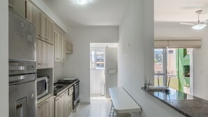 A modern kitchen with stainless steel appliances, a dining area with a bench, and a view of the outside. - Apt in Condo w/ Pool 350m From the Beach Pvj0021 (Ubatuba)