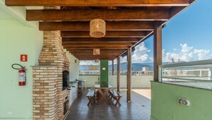 A covered outdoor area with a brick fireplace, wooden tables, and benches. - Apt in Condo w/ Pool 350m From the Beach Pvj0021 (Ubatuba)