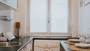 A kitchen with a washing machine, a sink, and a window with curtains. - Family Apartment City Center - Mirable PM (Milano)