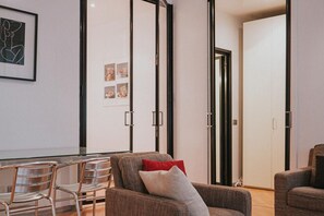 A modern living room with a glass dining table, metal chairs, and a sofa with cushions. - Family Apartment City Center - Mirable PM (Milano)